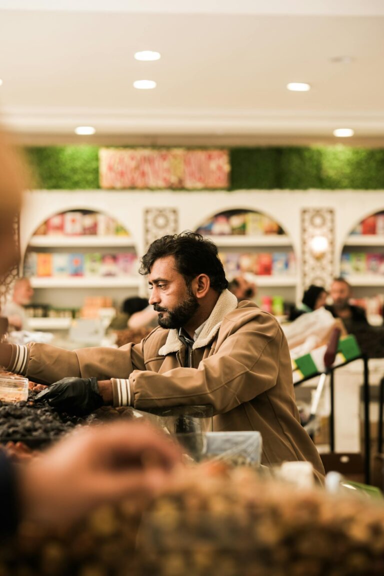 A focused man browsing goods in a lively Saudi Arabian market setting.
